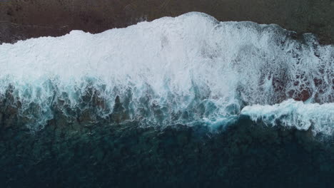 Aerial-:-Bird’s-eye-view-of-stormy-waves-crashing-on-coastline-of-Loyalty-islands,-New-Caledonia