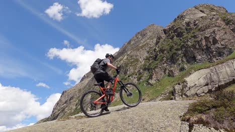 Uphill-mountain-bike-trail-ridig-on-a-big-rock-with-a-MTB-amazing-mountain-landscape-view-in-the-austrian-alps