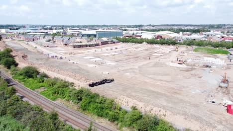 UK-town-housing-development-working-foundation-construction-site-aerial-view-pan-right