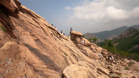 Eine-Gruppe-Von-Touristen,-Die-Einen-Felsigen-Hang-Hinaufklettern-Und-Die-Aussicht-Von-Der-Bergspitze-Im-Seoraksan-Nationalpark-In-Der-Provinz-Gangwon,-Südkorea,-Genießen