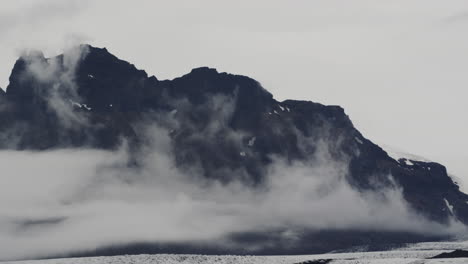 Cinematic-epic-shot-of-volcanic-cloud-covered-mountain-ranges-in-Fjallsárlón-Iceland