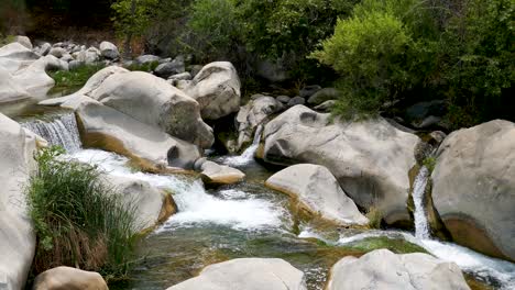 A-mountain-river-with-freshwater-flowing-through-a-narrow-rocky-riverbed-and-forming-a-small-pond