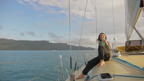 Beautiful-Woman-Sitting-On-A-Boat,-Offering-A-Cup-Of-Drink-While-Sailing-Across-Hook-Passage-In-Whitsunday-Islands,-QLD
