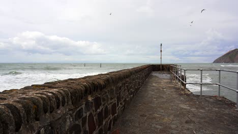 Waves-crash-around-the-harbor-wall-and-sea-defences-of-Lynmouth-on-a-windy-day