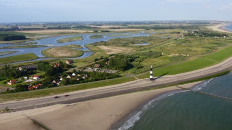 Aerial-seaside-approach-to-the-lighthouse-situated-onshore-with-the-panorama-of-Waterdunes---a-nature-area-and-recreational-park-in-the-province-of-Zeeland,-The-Netherlands
