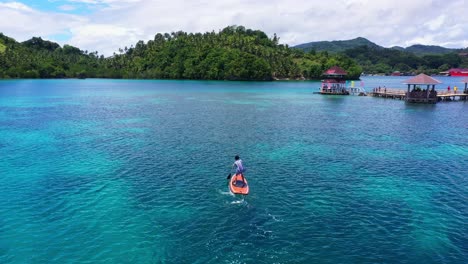 Männlicher-Tourist-Paddelt-In-Richtung-Der-Wasserhütten-Im-Tagbak-Marine-Park-In-Liloan,-Südliches-Leyte