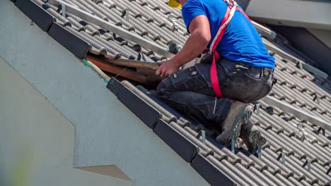 Close-up-of-repairman,-fixing-the-tiles-on-rooftop-of-hut