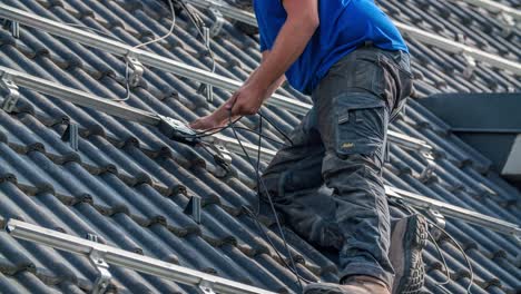 Close-up-shot-of-of-male-worker-connecting-electric-cable-of-solar-panels-on-rooftop
