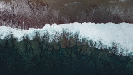 Bird's-eye-view-of-ocean-waves-crashing-against-shore-in-Loyalty-Islands,-New-Caledonia