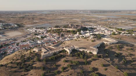 Ascending-shot-of-historical-fort-and-castle-in-Castro-Marim-with-vast-expanse-of-salt-pans-and-Guadiana-river