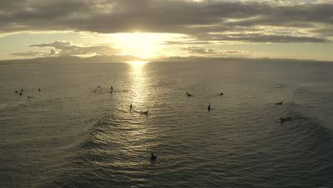 4k-Static-drone-shot-of-a-big-group-of-people-surfing-during-sunset-at-Byron-bay,-Australia
