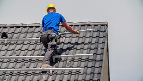 Caucasian-Technician-drilling-construction-for-solar-panels-on-rooftop,slowmotion