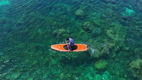 Male-Tourist-Rowing-On-An-Orange-Paddle-Board-At-The-Clear-Water-Of-Tagbak-Marine-Park