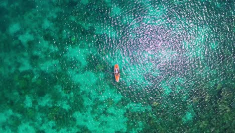 Top-View-Of-A-Male-Tourist-Lying-On-The-Orange-Paddle-Board-Amidst-The-Clear-Water-Of-Tagbak-Marine-Park