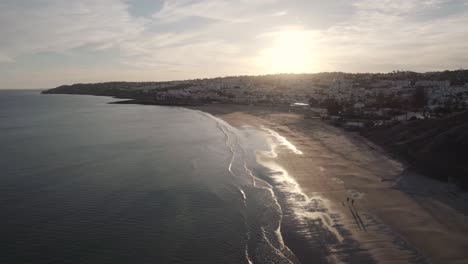 Praia-da-Luz-coastline-reflecting-golden-sunset-light,-Algarve