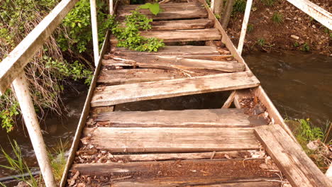 Damaged-wooden-bridge-over-a-small-river-in-the-forest
