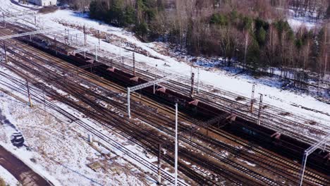 A-long-freight-train-of-empty-goods-wagons-in-Katowice-Poland---Drone-aerial-reveal-of-surrounding-countryside---Cold-snow-covered-landscape