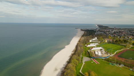 Aerial-view---drone-slowly-spinning-from-Wladyslawowo-baltic-sea-beach-to-the-city-panorama-revealing-school,-main-road-and-private-buildings-located-in-bay-area