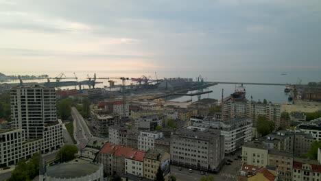 Panorama-Aéreo-Del-Puerto-De-Gdynia-Y-El-Distrito-Residencial-En-Una-Puesta-De-Sol-Nublada,-Terminal-Portuaria-De-Contenedores-De-Carga-Marina-En-El-Fondo