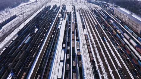 Long-straight-lines-of-freight-trains-in-the-rail-depot-at-Katowice-Poland---Drone-aerial-reveal---Winter-snow-covered-railway-lines