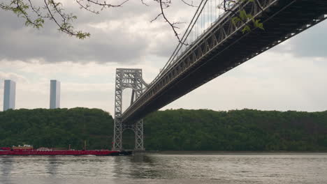 Der-Rote-Lastkahn-Bahnt-Sich-Seinen-Weg-Unter-Der-GW-Brücke,-Während-Er-Den-Hudson-River-Hinauf-Und-An-Upper-Manhattan-Vorbeiführt