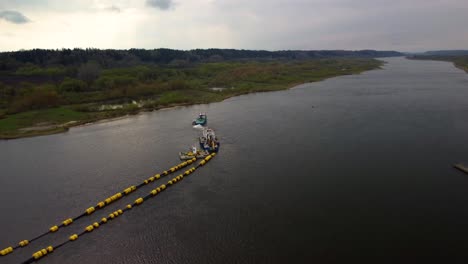aerial-shot-of-green-boat-pulling-another-boat-with-a-buoy-in-the-river