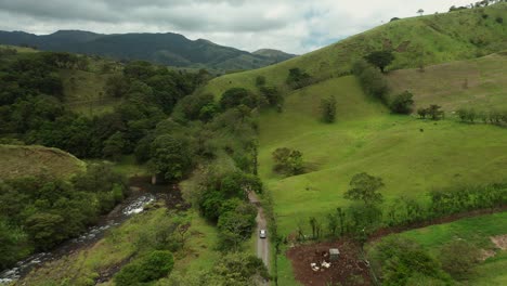 Rural-green-landscape-of-Costa-Rica-with-car-driving-on-dirt-road