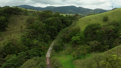 Car-driving-through-lush-jungle-forest-with-green-grass-mountainside