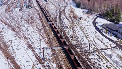 Aerial-drone-shot-following-a-long-empty-freight-train-through-the-snow-covered-winter-landscapes-of-Katowice-Poland