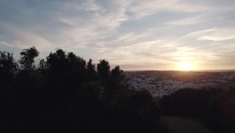 Sunsetting-behind-Rocha-Negra-shrubs-at-Praia-da-Luz,-Algarve---Aerial