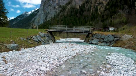 Low-and-close-aerial-drone-fly-through-flight-below-a-bridge-at-scenic-Ahornboden-Engtal-valley-along-Rissach-mountain-river-in-the-Bavarian-Austrian-alps-on-a-cloudy-and-sunny-day-in-nature