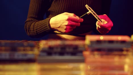 Woman-using-a-tool-to-wind-the-tape-on-a-vintage-cassette---sliding-view-with-stacks-of-cassettes-in-the-foreground
