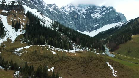 Aerial-drone-flight-at-scenic-Ahornboden-Engtal-valley-toward-the-snowy-glacier-mountain-tops-in-the-Bavarian-Austrian-alps-on-a-cloudy-and-sunny-day-along-trees,-rocks,-forest-and-hills-in-nature