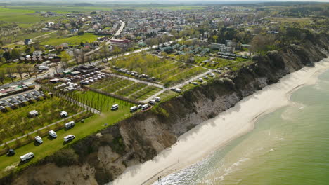 Camper-trailers-campsite-on-a-cliff-in-Chlapowo-beach,-Poland,-aerial-fly-over-on-sunny-day
