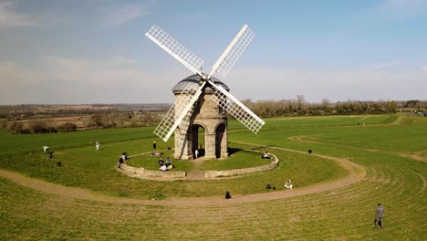 Tourists-enjoying-sunny-Chesterton-Windmill-aerial-low-orbit-left-view-over-picturesque-English-rural-countryside-farmland