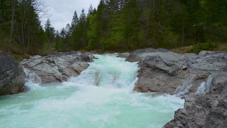 Rissach-river-flowing-down-a-scenic-and-idyllic-mountain-canyon-with-fresh-blue-water-along-green-lush-trees-in-the-Bavarian-Austrian-alps-close-to-Engtal,-Ahornboden-and-Walchensee-lake