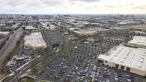 City-of-Tustin,-aerial-view-over-building-and-parking-lot-of-cars