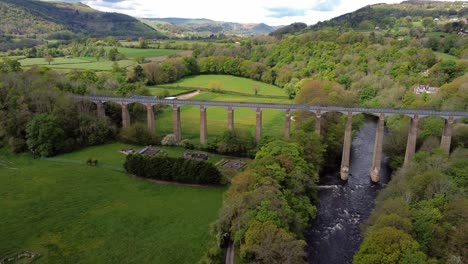 Aerial-view-Pontcysyllte-aqueduct-and-River-Dee-canal-narrow-boat-bride-in-Chirk-Welsh-valley-countryside-pull-away-left-tilt-up