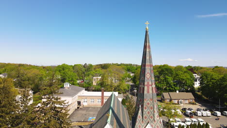St-Paul's-Church-in-Hingham-MA,-Aerial-upward-footage-revealing-Boston-Skyline-in-the-distance