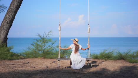 A-young-woman-in-a-flowing-dress-enjoys-a-swing-with-an-ocean-view