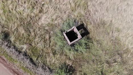 Aerial-drone-shot-of-an-abandoned-guard-house-in-a-field