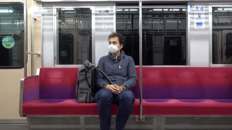 Ein-Einsamer-Mann-Mit-Gesichtsmaske-Sitzt-Während-Der-Koronakrise-In-Einem-Hellen-Zug