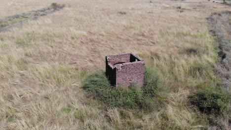 Aerial-drone-shot-of-an-abandoned-guard-house-in-a-field