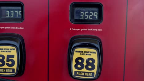 Red-and-black-gas-pumps-with-prices-super-high-over-three-dollars,-panning-left-to-right-to-show-unleaded,-medium,-and-premium-grade-fuel-prices---in-4K-slow-motion