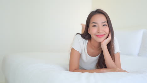 A-young-woman-lying-on-a-hotel-suite-bed-smiles