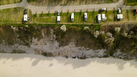 Aerial-view-of-Chlapowo-campsite-with-many-camper-trailers-parked-on-a-cliff-beach-front-of-Baltic-sea,-Poland-travel-spot