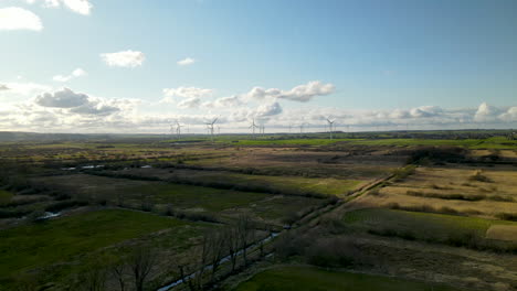 Aerial-wide-view-of-wind-farm-in-rural-spring-landscape-during-sunlight-outdoors-in-nature