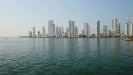 Drone-Flies-Above-People-on-Fishing-Boat,-Cartagena-Skyline-in-Background