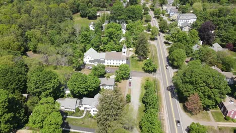 Aerial-pull-back-rising-shot-over-typical-rural-American-countryside-town-in-Massachusetts-with-a-church-as-the-center-focus