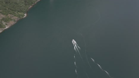 Slow-aerial-circular-shot-of-cruising-boat-in-Geiranger-fjord,-Norway